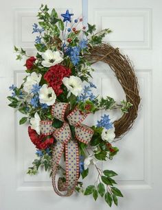 a wreath with red, white and blue flowers hanging on a door