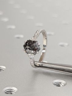 a diamond ring sitting on top of a metal table next to some screwdrivers