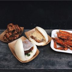 three plates with food on them sitting on a wooden table next to some bread sticks