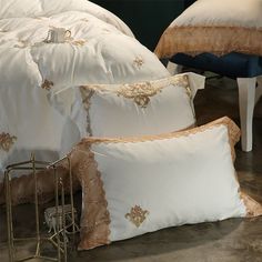 three pillows with gold trim on them sitting next to each other in front of a bed