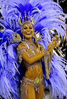 a woman in a purple and gold costume with feathers on her head is smiling at the camera