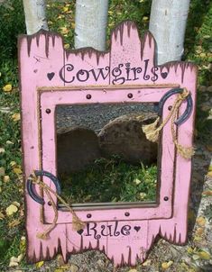 a pink frame with the word cowgirls written on it and two trees in the background