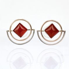 A pair of fine pair of retro geometric earrings.  In gold & silver with carnelian cabochons.  By Yumi Ueno.   Ueno is a Japanese-American jewelry artist, whose fine and whimsical jewelry is informed by three-dimensional geometric abstraction. She works in varied metals including gold and sterling silver and incorporates precious and semi-precious stones in many of her works. Ueno has received numerous awards and has regularly exhibited internationally and on both US coasts.  Simply a wonderful pair of vintage earrings!  Date: 20th Century  Overall Condition: They are in overall good, as-pictured, used estate condition with some very fine & light surface scratches and other signs of expected light wear consistent with age.  Fineness: Unmarked for fineness. Professionally tests at 14K.  Mark Modern Cabochon Earrings For Formal Occasions, Modern Red Cabochon Jewelry, Modern Gold Cabochon Earrings, Art Deco Earrings With Polished Finish, Modern Orange Sterling Silver Jewelry, Modern Red Round Earrings, Modern Carnelian Jewelry For Formal Occasions, Modern Sterling Silver Earrings With Cabochon, Modern Cabochon Earrings Gift