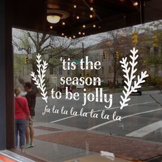 two children are looking out the window at an outside cafe that says tis the season to be jolly