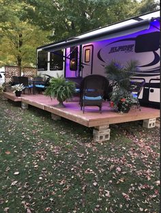 an rv is lit up with purple lights in the back yard and decking area