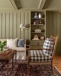 a living room filled with furniture and green painted wood paneled walls, along with a rug on the floor