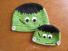 two crocheted hats sitting on top of a wooden table