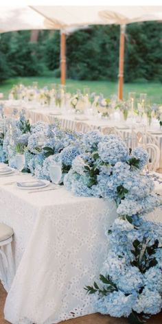 the tables are covered with white tablecloths and blue hydrangeas on them