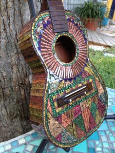 a colorful guitar sitting on top of a blue table next to a tree and building