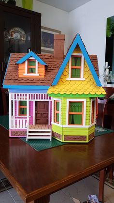 a wooden table topped with two colorful doll houses