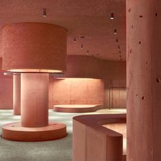 an empty room with pink walls and round lights on the ceiling, surrounded by concrete pillars