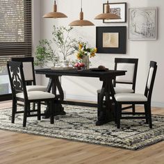 a dining room table with four chairs and a rug on the floor in front of it