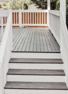 a white porch with steps leading up to the front door and trees in the background