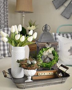 white tulips are in vases on a tray next to an old book