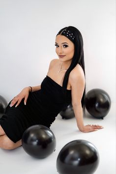 a woman in a black dress sitting on some balloons