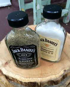 two bottles of spices sitting on top of a wooden stump