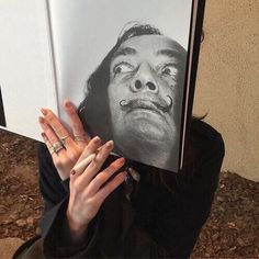 a woman holding up a book with an image of a man's face on it