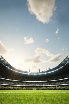 an empty soccer stadium with the sun shining down on it's field and grass