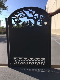 a person is holding up a metal gate that looks like a tree with people on it