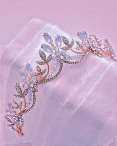 a close up of a tiara on top of a white cloth with pink background