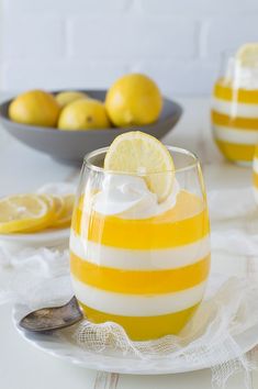 a dessert with lemons and whipped cream in a glass on a white tablecloth