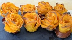 several yellow roses sitting on top of a wooden table next to each other and one is dying