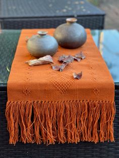 an orange table runner with two vases on it