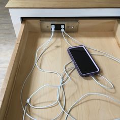 an electronic device is plugged into the charging station in this kitchen drawer, which also has cords attached to it