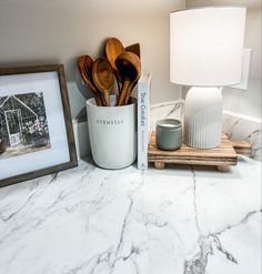 kitchen utensils are sitting on a marble countertop next to a framed photograph