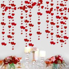 a table topped with lots of red hearts hanging from the side of it's wall