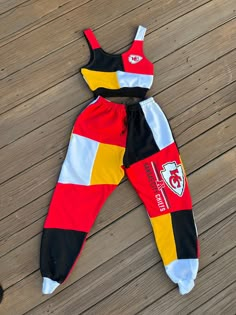 a child's red, yellow and black outfit laying on top of a wooden floor