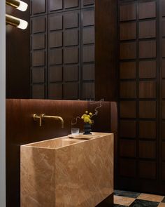 a bathroom sink sitting under a mirror next to a wooden cabinet and wall mounted faucet