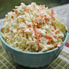 a bowl filled with coleslaw and carrots on top of a green table cloth