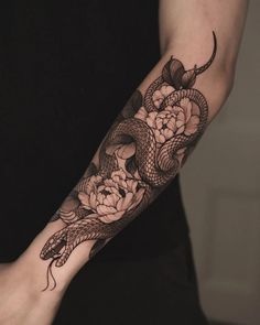 a woman with a snake and flowers tattoo on her arm