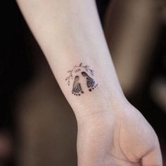 a small tattoo on the wrist of a woman's left hand, with footprints and flowers