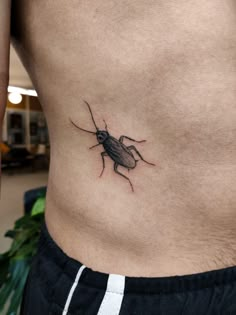 a small insect tattoo on the side of a man's stomach