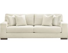 a white couch with four pillows on it's back and one arm facing the camera