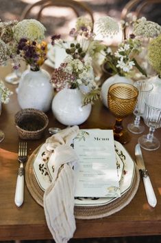 the table is set with plates, silverware and flowers