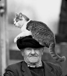 an old man wearing a hat with a cat on top of his head in black and white