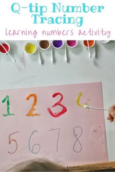 a child's hand is painting numbers on a piece of paper