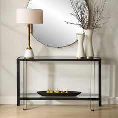 a table with a mirror and vases on it next to a bowl of lemons