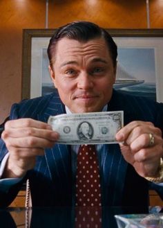 a man in a suit holding up a dollar bill