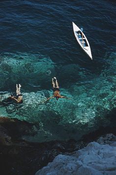 two people swimming in the ocean near a boat