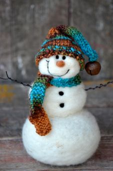 a small snowman with a knitted hat and scarf on it's head