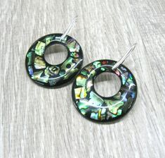 Round abalone paua earrings, Donut earrings, natural shell earrings in sterling silver Rainbow abalone ocean jewelry wide hoop earrings Length: 50 mm from ear hole to the bottom. These earrings are made in mosaic technique out of abalone paua shell pieces in resin. The round charm measures 37 mm in diameter and is 2 mm thick. The hole measures 16 mm in diameter. This shell charm is made of a round piece of white mother of pearl ( see the back side photos ) with rainbow abalone set in resin in fr Iridescent Round Jewelry With Ear Wire, Handmade Iridescent Round Jewelry, Unique Iridescent Round Jewelry, Unique Nickel-free Mother Of Pearl Jewelry, Pierced Round Mother Of Pearl Jewelry, Adjustable Round Mother Of Pearl Earrings, Abalone Shell Dangle Jewelry, Silver Abalone Shell Drop Earrings, Silver Jewelry With Abalone Shell Ear Wire