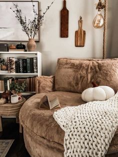 a living room filled with furniture and books on top of a brown ottoman next to a book shelf