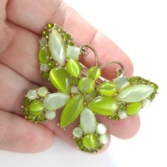 *Description: This is a beautiful light green butterfly brooch by Monet with glass cabochons which look like moonstone as it moves under the light. In addition to the glass cabochons are light green rhinestones on a gold tone background. This would be a great addition to your vintage jewelry collection or make a great vintage gift! *Approximate Measurements: Length - 2 Inches, Width - 2 1/4 Inches *Condition: Great vintage condition. Will see signs of wear under magnification. See photos for det Green Butterfly Brooch Jewelry, Light Green Butterfly, Green Moonstone, Formal Earrings, Vintage Christmas Gifts, Book Pieces, Curling Ribbon, Green Butterfly, Butterfly Brooch