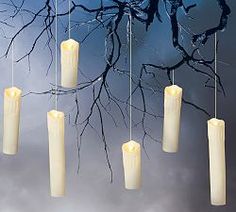 a group of candles hanging from strings in front of a tree with no leaves on it