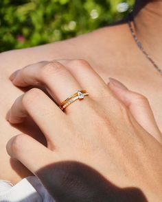 a woman's hand wearing a gold ring with two diamonds on the middle finger