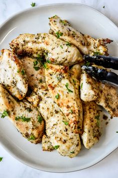 a white plate topped with chicken covered in herbs